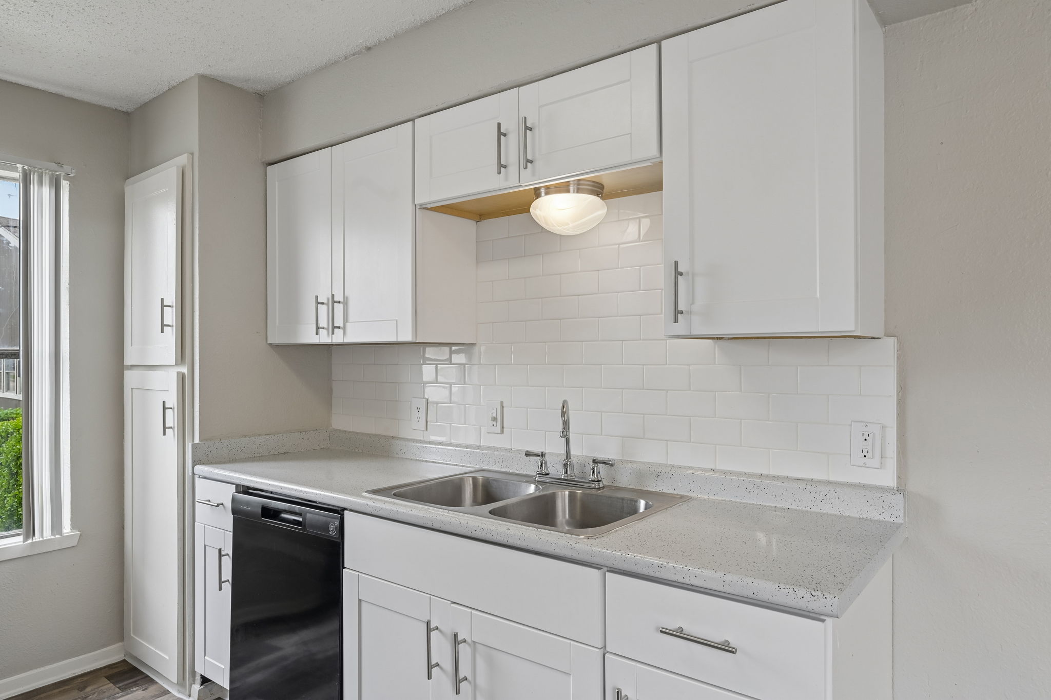 A kitchen with white cabinets and a black dishwasher.